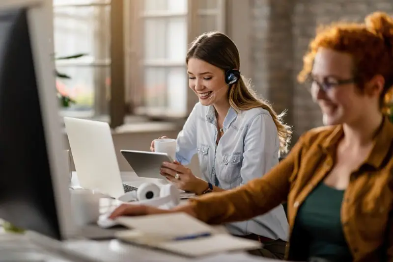 Primeiro Contato Com o Lead: Conquiste o Seu Cliente No Início 1 happy female entrepreneur with headset drinking coffee while surfing net touchpad office 800